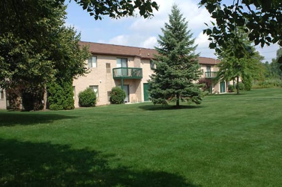 a large brick building with a green lawn and trees