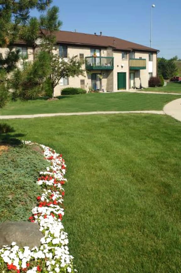 a white and red flower garden in front of a house