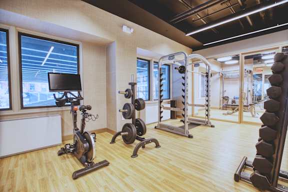 A gym with a variety of equipment including a stationary bike, a squat rack, and a bench press.