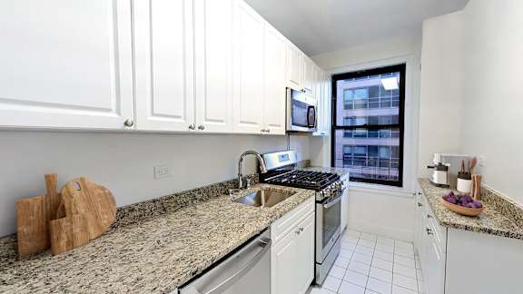 A kitchen with white cabinets and granite countertops. at Sutton Collection Apartments, New York, 10022