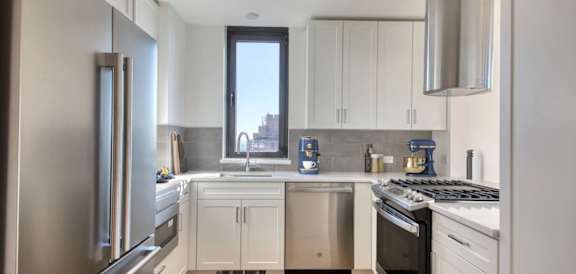 A modern kitchen with white cabinets and stainless steel appliances.