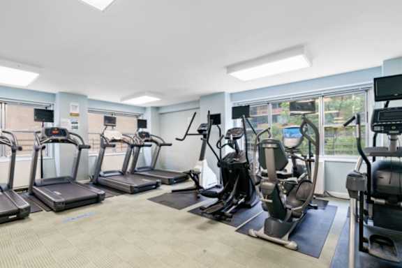 A gym with treadmills, exercise bikes, and other equipment  at The Caldwell Apartments, New York, 10028