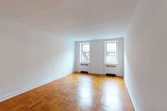 A room with wooden floors and two windows.