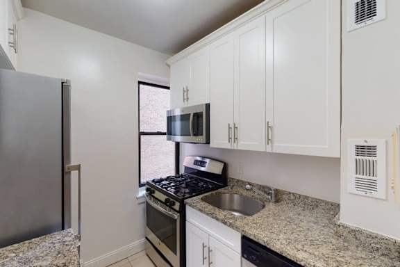 A kitchen with granite countertops and white cabinets.