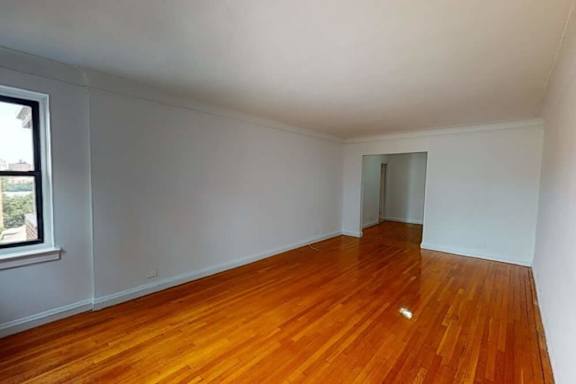 A room with wooden flooring and white walls.