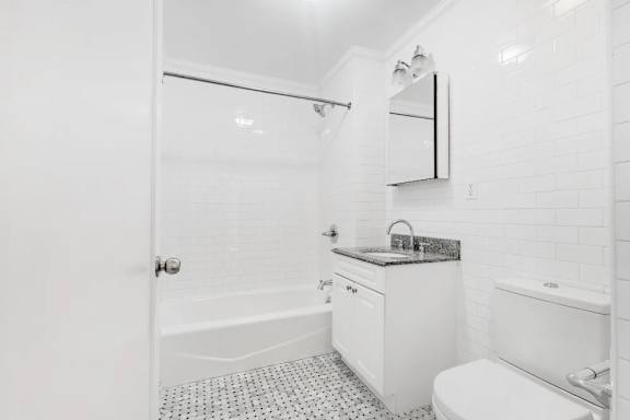 A white bathroom with a shower, toilet, and sink.