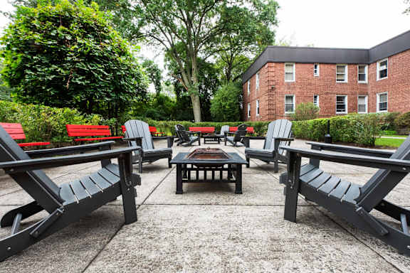 A patio with black benches and a table surrounded by greenery.