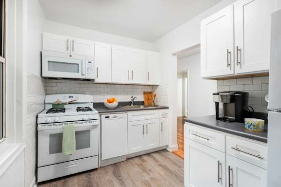 A white kitchen with a stove, microwave, and refrigerator.