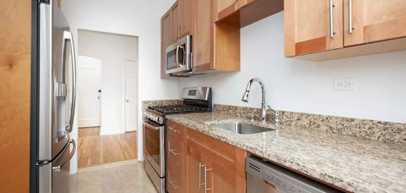 A kitchen with granite countertops and wooden cabinets. at Sutton Collection Apartments, New York, New York
