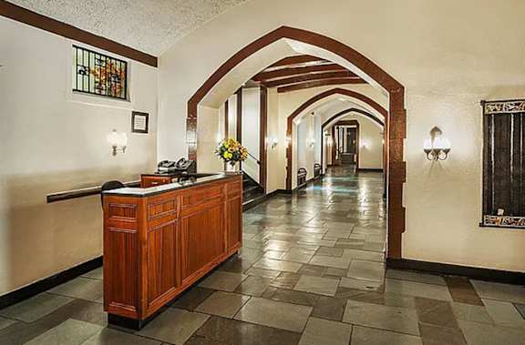 A hallway with a wooden reception desk and a vase of flowers on top. at Sutton Collection Apartments, New York, NY, 10022