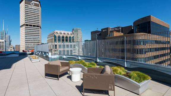 A rooftop patio with a table and chairs overlooking a city skyline.