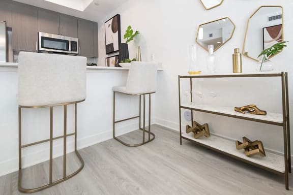 two bar stools in a living room with a counter and a microwave