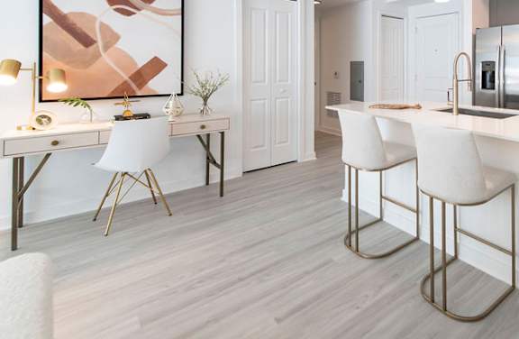 A modern kitchen with white chairs and a wooden floor.