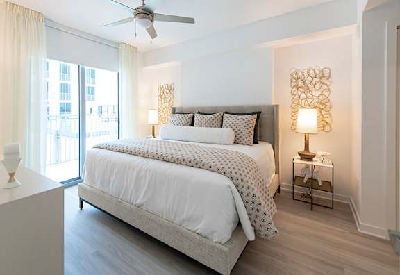 A bedroom with a large bed and a ceiling fan.