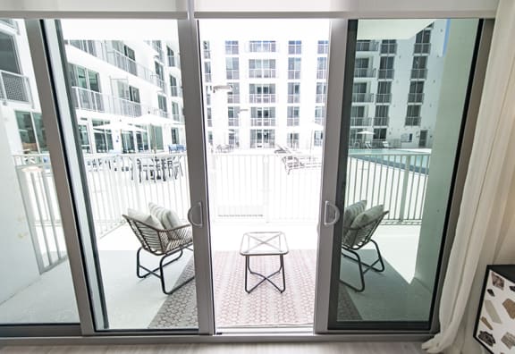 a balcony with chairs and a table in front of a glass door