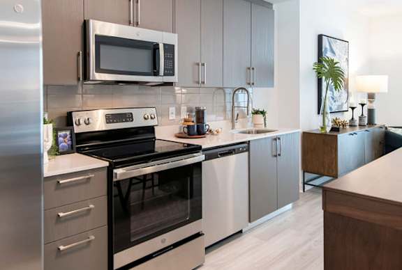A modern kitchen with stainless steel appliances and a wooden counter.