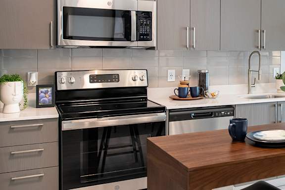 A modern kitchen with a black stove top oven and a microwave above it.