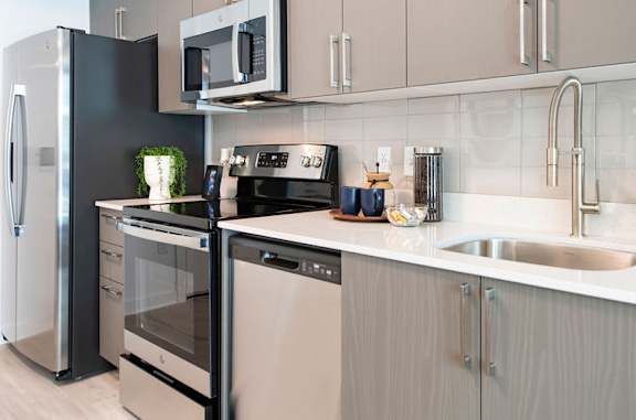 A modern kitchen with stainless steel appliances and a white countertop.