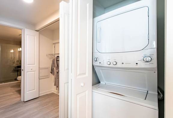 A white dryer is in a laundry room with a door open.