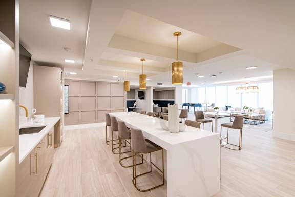 A modern kitchen with a long white island and stainless steel appliances.