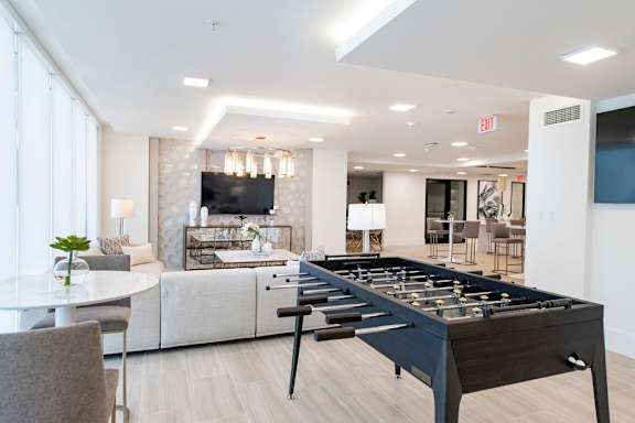 A foosball table is in the middle of a room with a couch and a television.