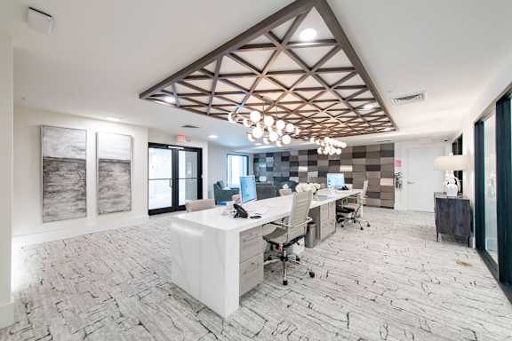 A modern office space with a large desk and chairs.