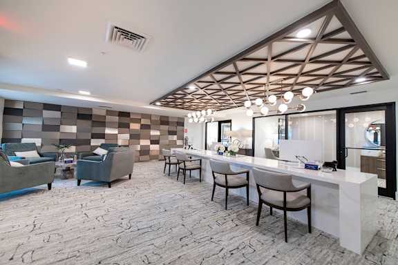A modern office with a reception desk and chairs.