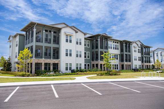 A large, modern building with a parking lot in front.