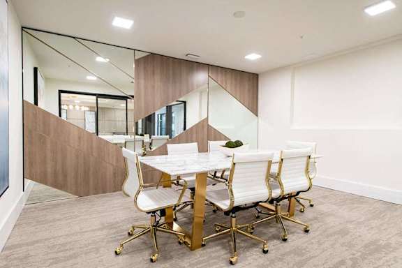 A conference room with a table surrounded by white chairs.