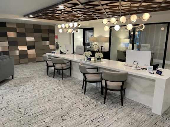 A well-lit salon with a white counter and brown chairs.