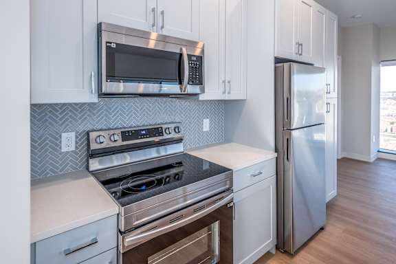 A kitchen with a stove top oven, microwave, and refrigerator at 7 West 7th Apartments, Ohio