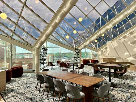 A modern dining room with a glass ceiling and wooden furniture at 7 West 7th Apartments, Cincinnati, OH 45202