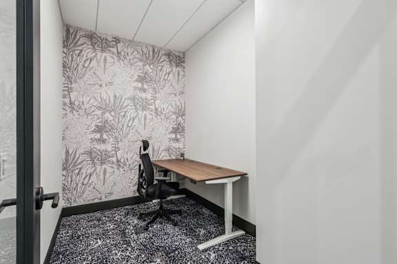 A small room with a desk and a plant pattern wallpaper at LiveWell Apartments, Pittsburgh, PA, 15222