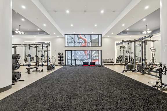 A spacious gym with a variety of equipment and a large mirror on the wall at LiveWell Apartments, Pittsburgh, PA, 15222