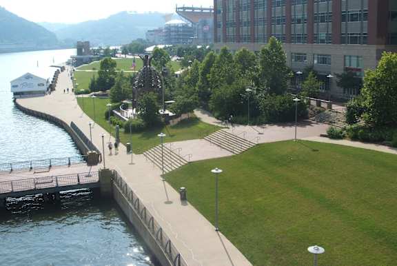 A park with a grassy area, a walkway, and a body of water. at LiveWell Apartments, Pittsburgh 15222