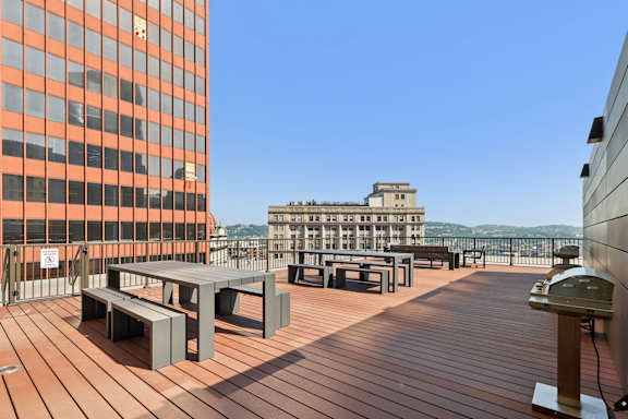 A wooden deck with benches and a table with a building in the background. at LiveWell Apartments, Pennsylvania