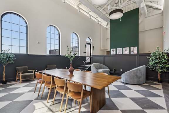 A long wooden table is surrounded by chairs in a room with a checkered floor at LiveWell Apartments, Pittsburgh 15222