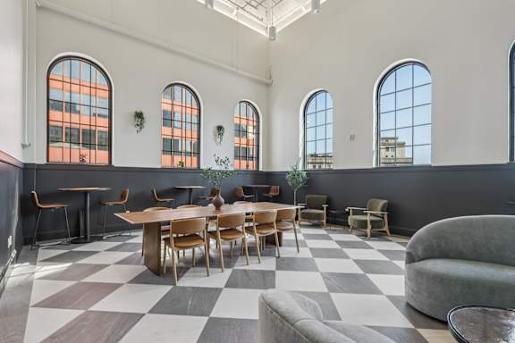 A large room with a checkered floor and a long table with chairs. at LiveWell Apartments, Pittsburgh, PA