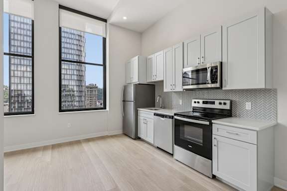 A kitchen with white appliances and cabinets. at LiveWell Apartments, Pittsburgh, PA, 15222