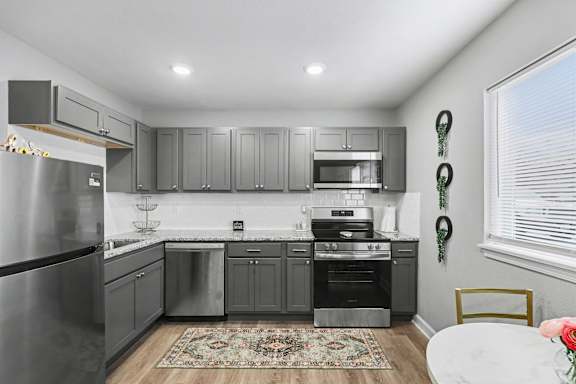 Floor Plan  A modern kitchen with stainless steel appliances and grey cabinets.