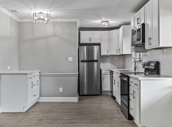 A kitchen with white cabinets and a stainless steel refrigerator.