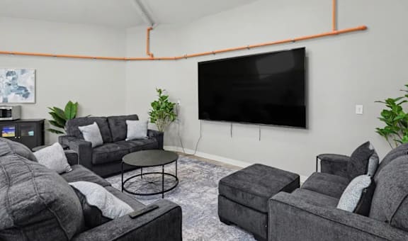 A living room with grey couches and a black television. at Mayfair Apartments, Kansas City, Missouri