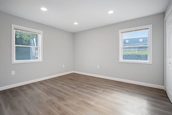 A room with light grey walls and a wooden floor at Palisades Apartments in Kansas City, MO 64133