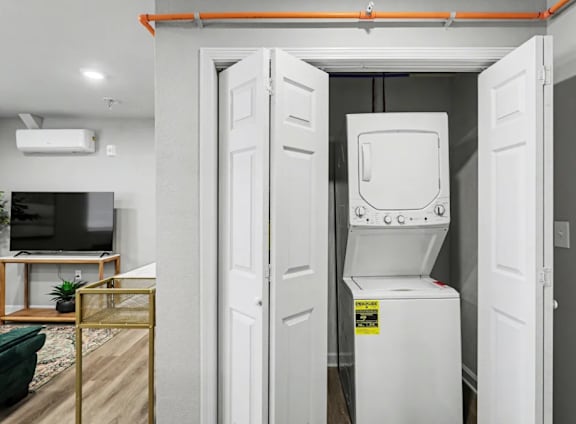 A white tankless water heater in a room with a television and a plant. at Mayfair Apartments, Kansas City