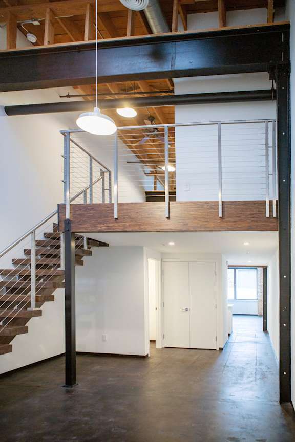 a loft with a staircase and white walls and a white door