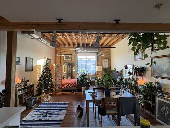 a living room and dining room with a bed in the background