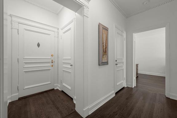 A hallway with white doors and wood floors..