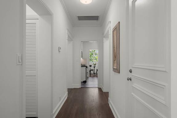 A long hallway with white walls and wood floors.