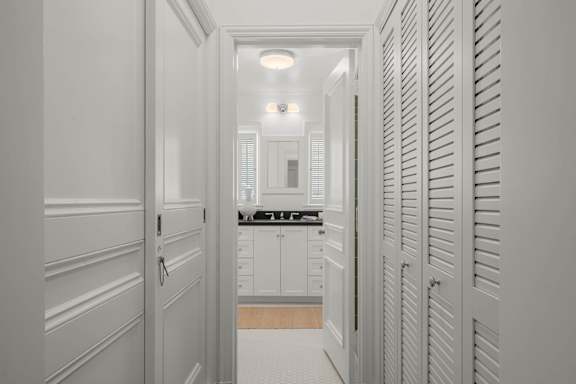 A hallway with white walls and a kitchen in the distance.
