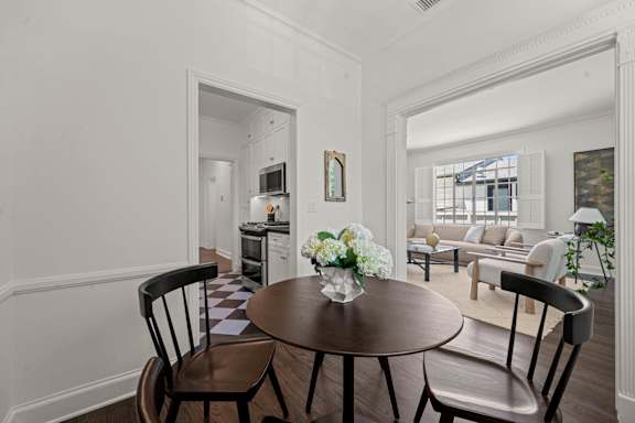 A dining room with a table set for two and a vase of flowers.